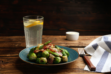 Delicious Brussels sprouts with bacon on wooden table