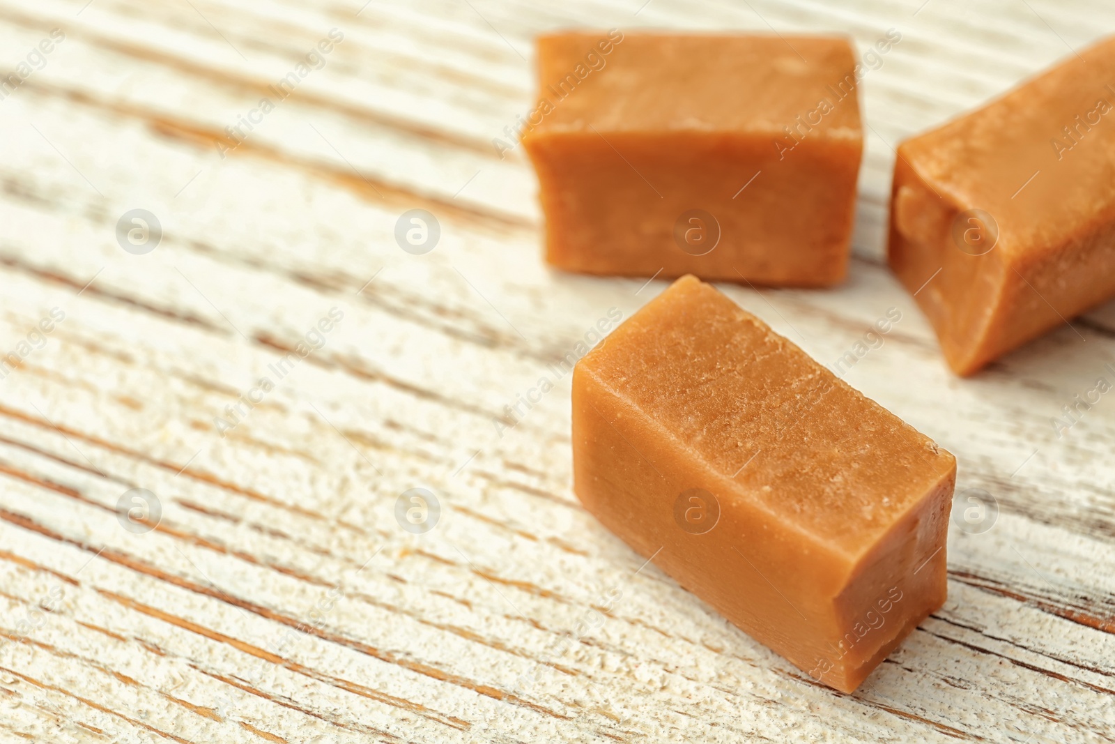 Photo of Delicious caramel candies on wooden background