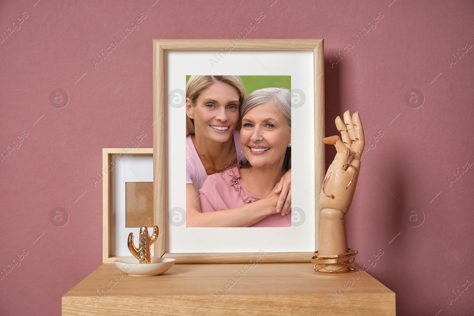 Image of Family portrait of mother and daughter in photo frame on table near color wall
