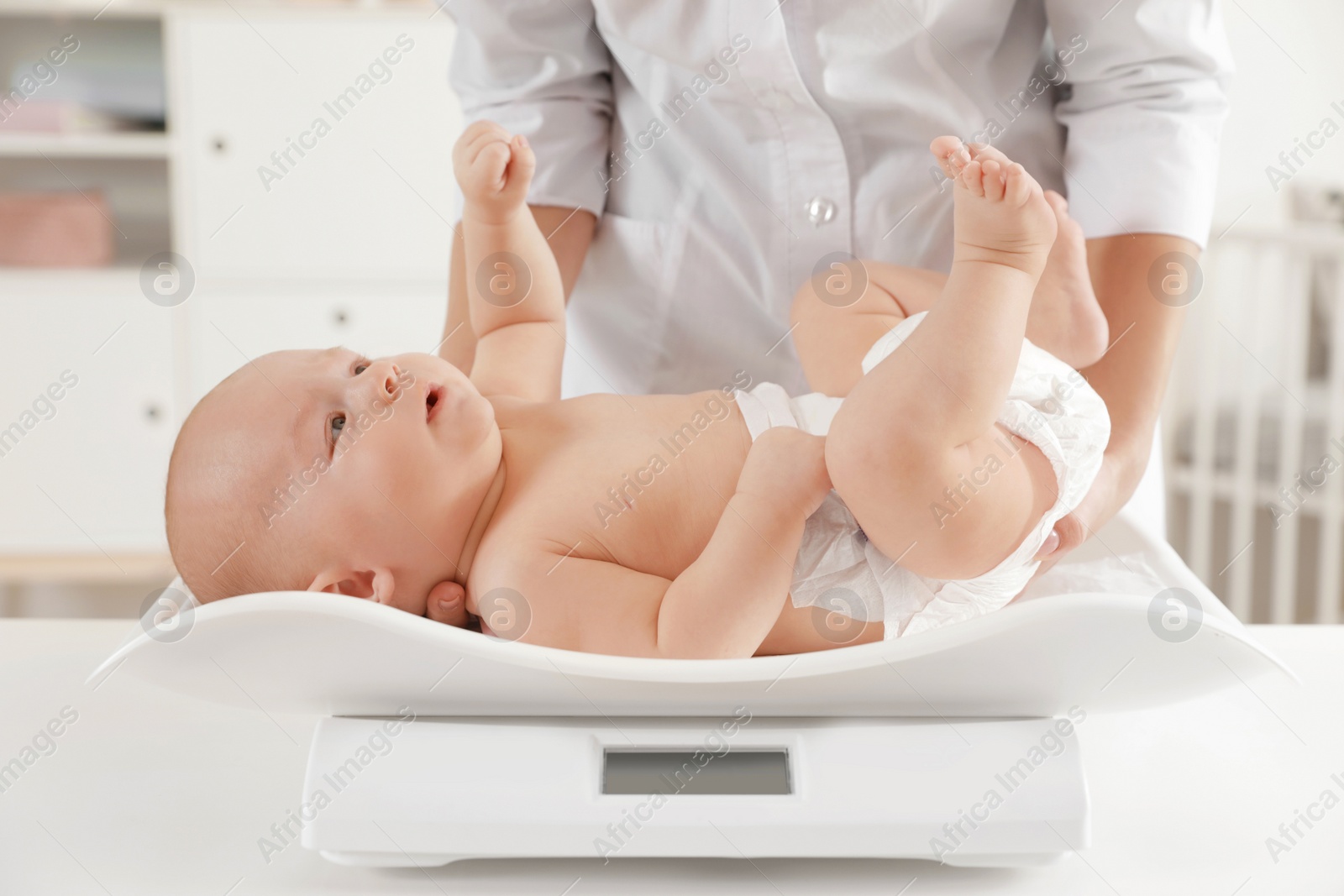 Photo of Doctor weighting baby on scales in light room