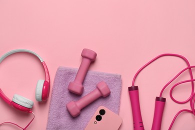 Photo of Flat lay composition with dumbbells and smartphone on pink background. Space for text