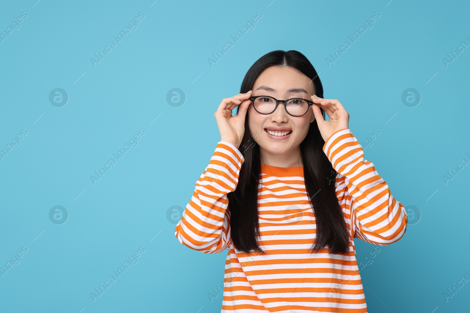 Photo of Portrait of happy woman in glasses on light blue background. Space for text