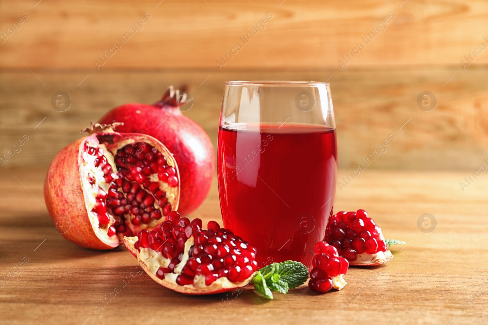 Photo of Glass of pomegranate juice and fresh fruits on wooden table