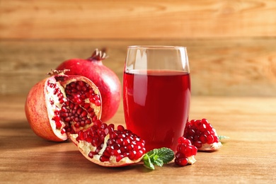 Photo of Glass of pomegranate juice and fresh fruits on wooden table