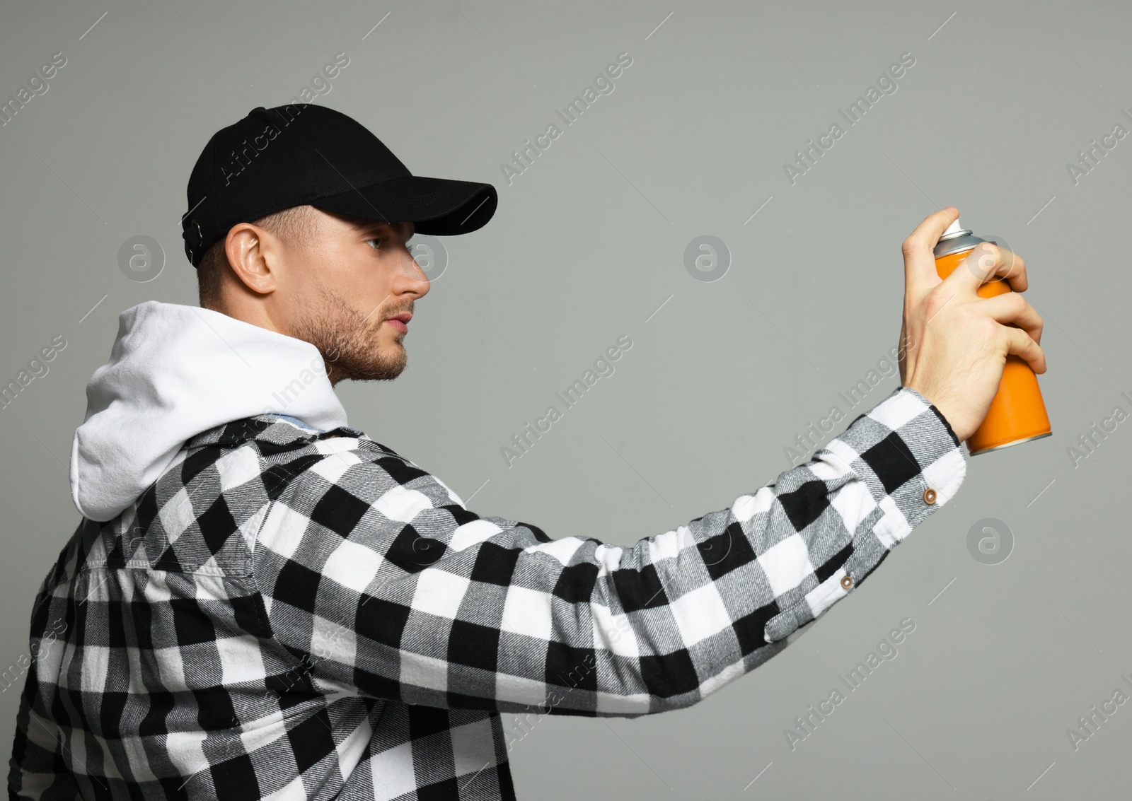 Photo of Handsome man holding orange can of spray paint on grey background