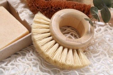 Photo of Cleaning brush, soap bar and eucalyptus leaves on table, closeup