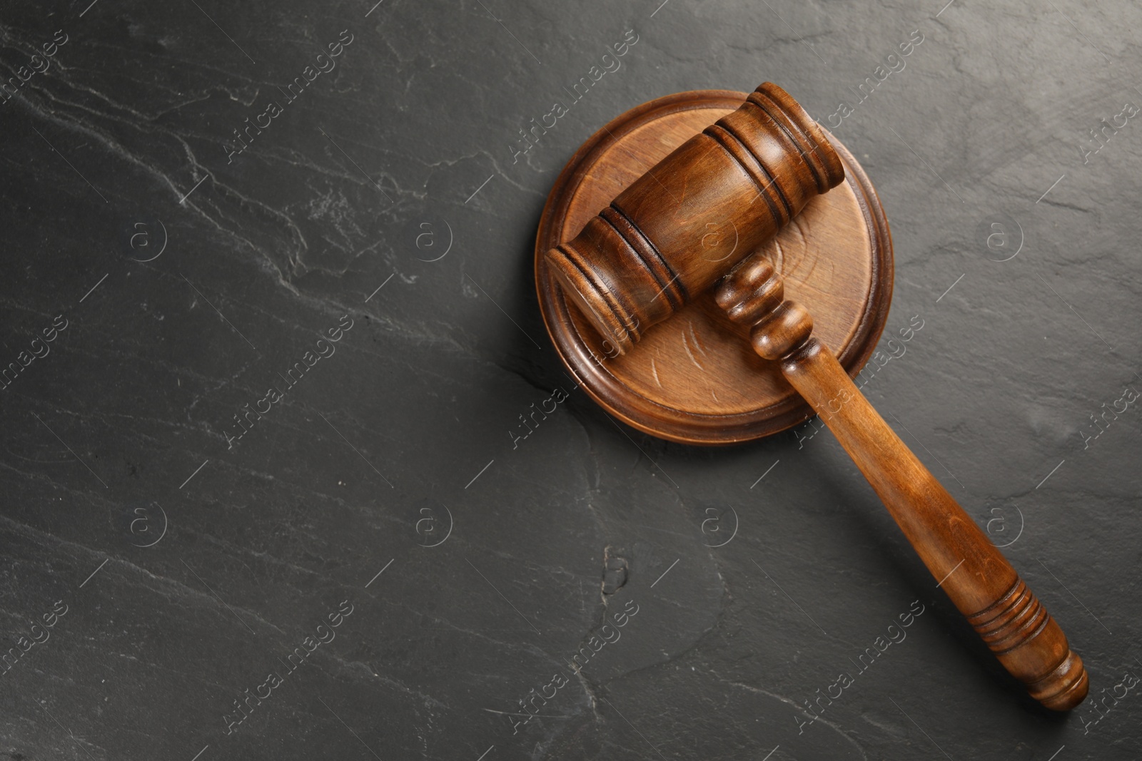 Photo of Wooden gavel on dark textured table, top view. Space for text