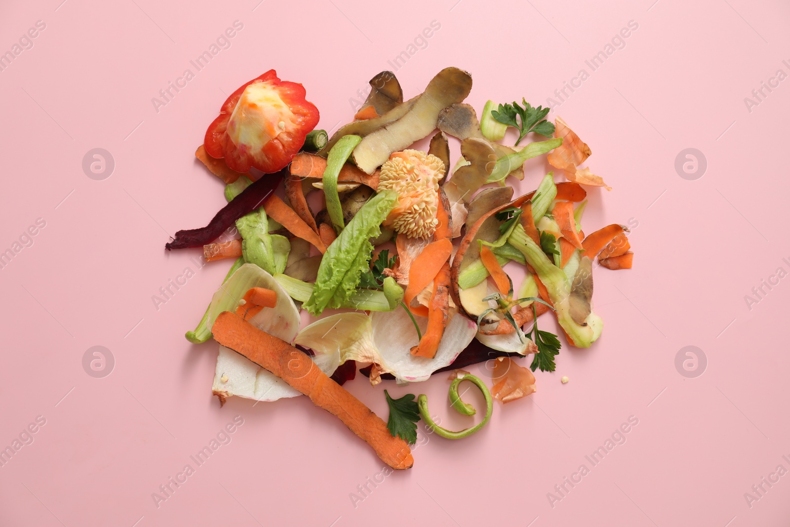 Photo of Peels of fresh vegetables on pink background, flat lay