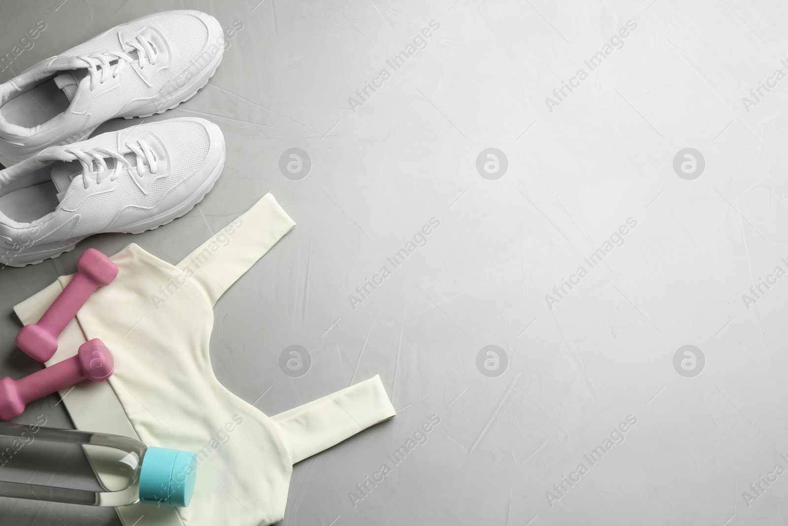 Photo of Flat lay composition with sportswear and equipment on light grey table, space for text. Gym workout