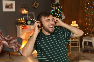 Happy young man listening to Christmas music at home