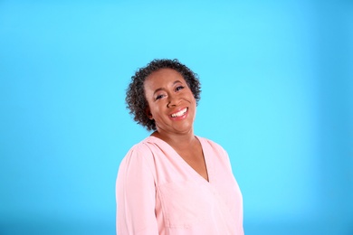 Portrait of happy African-American woman on light blue background