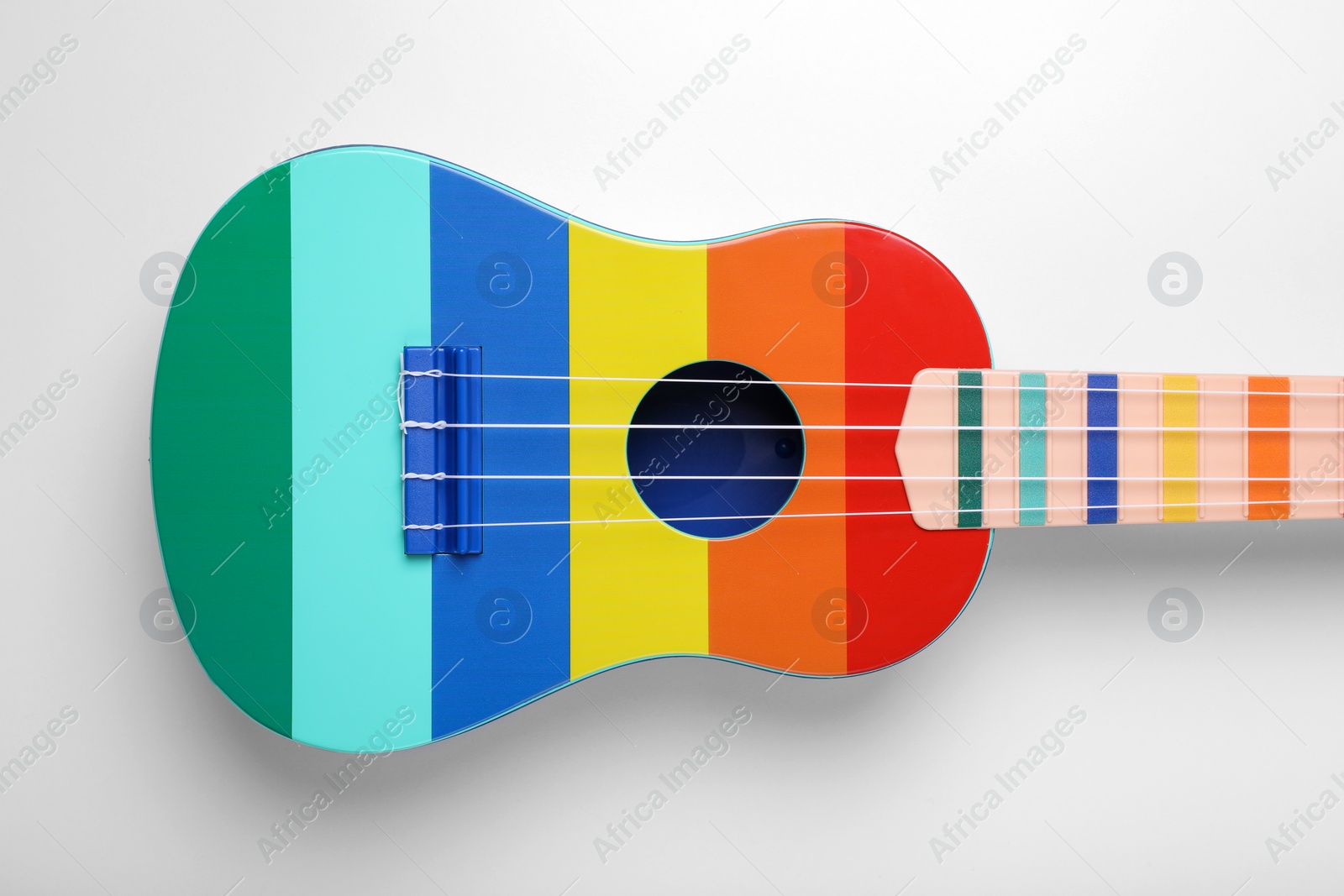 Photo of Colorful ukulele on white background, top view. String musical instrument