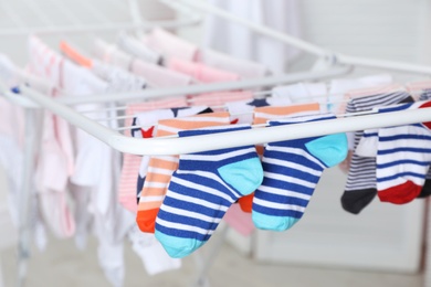 Photo of Different colorful socks on drying rack against blurred background, closeup