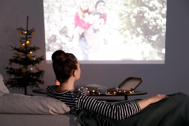 Photo of Woman watching romantic Christmas movie via video projector at home