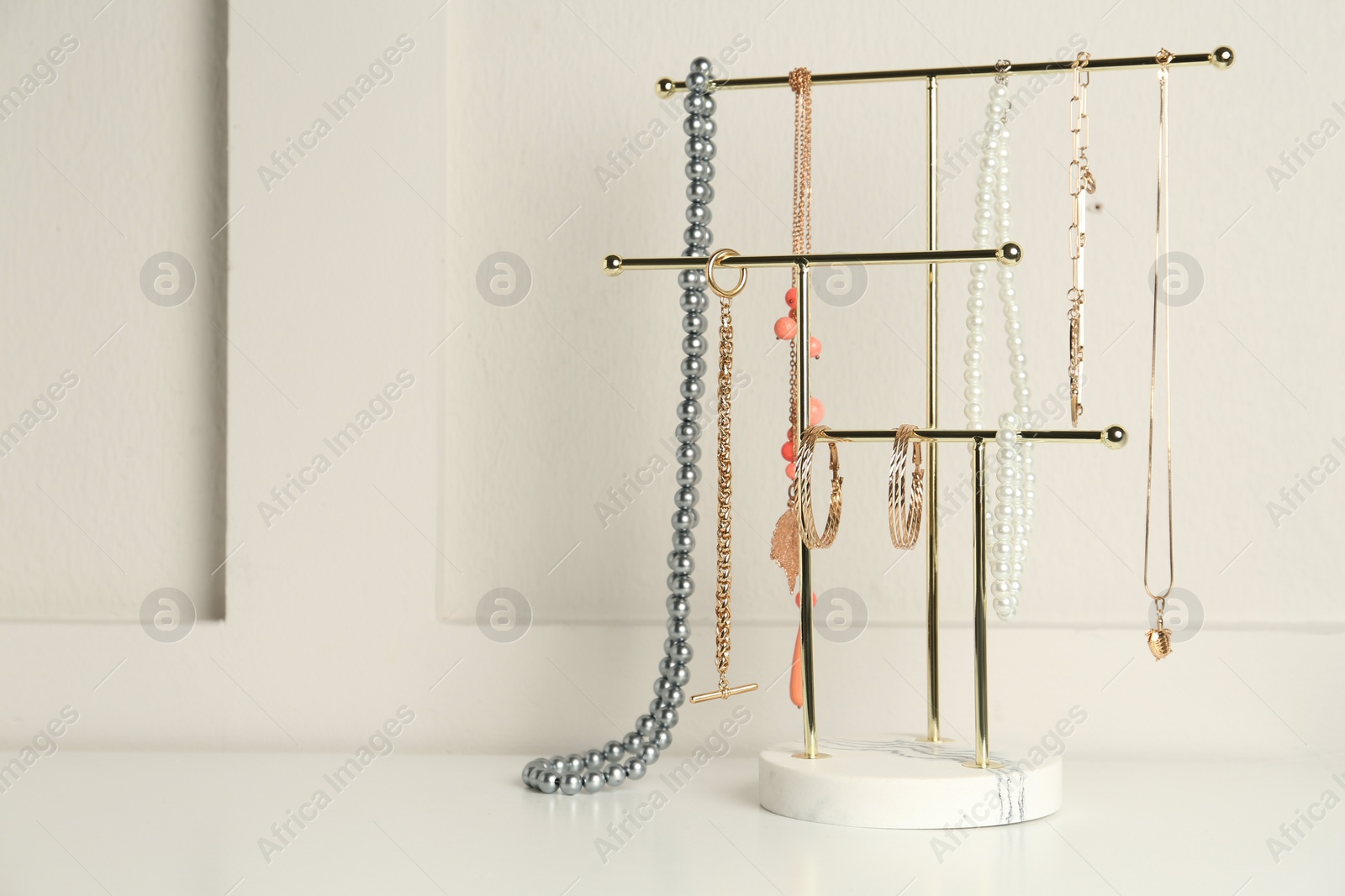 Photo of Holder with set of luxurious jewelry on white table. Space for text