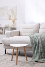 Photo of Knitted plaid on comfortable sofa in living room