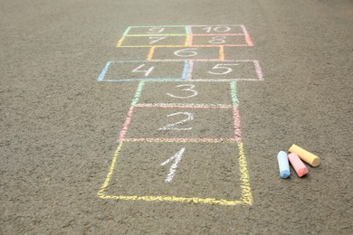 Hopscotch drawn with colorful chalk on asphalt outdoors, closeup