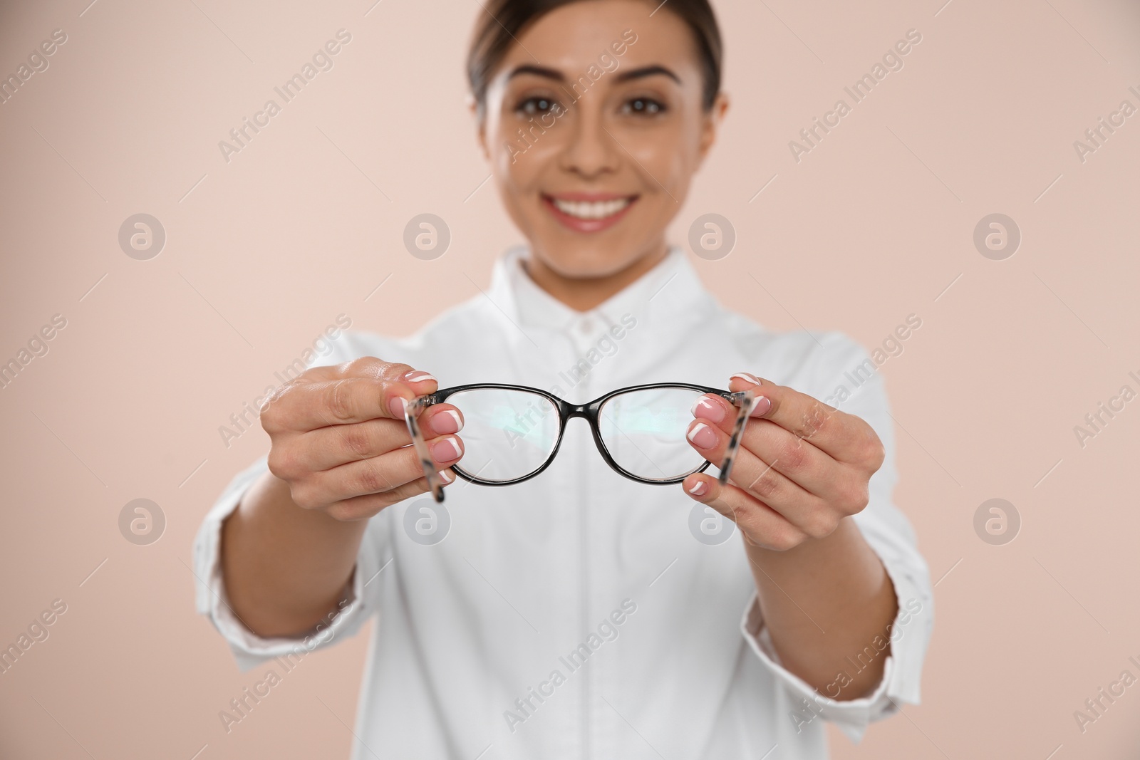 Photo of Female ophthalmologist with eyeglasses on light background