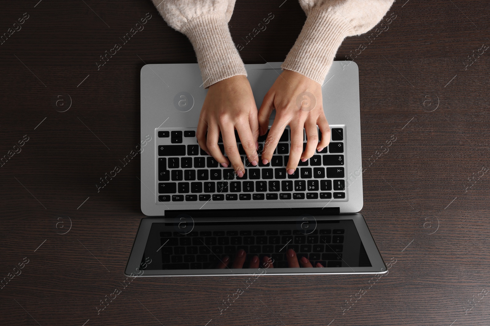 Photo of Woman working with laptop at wooden table, top view