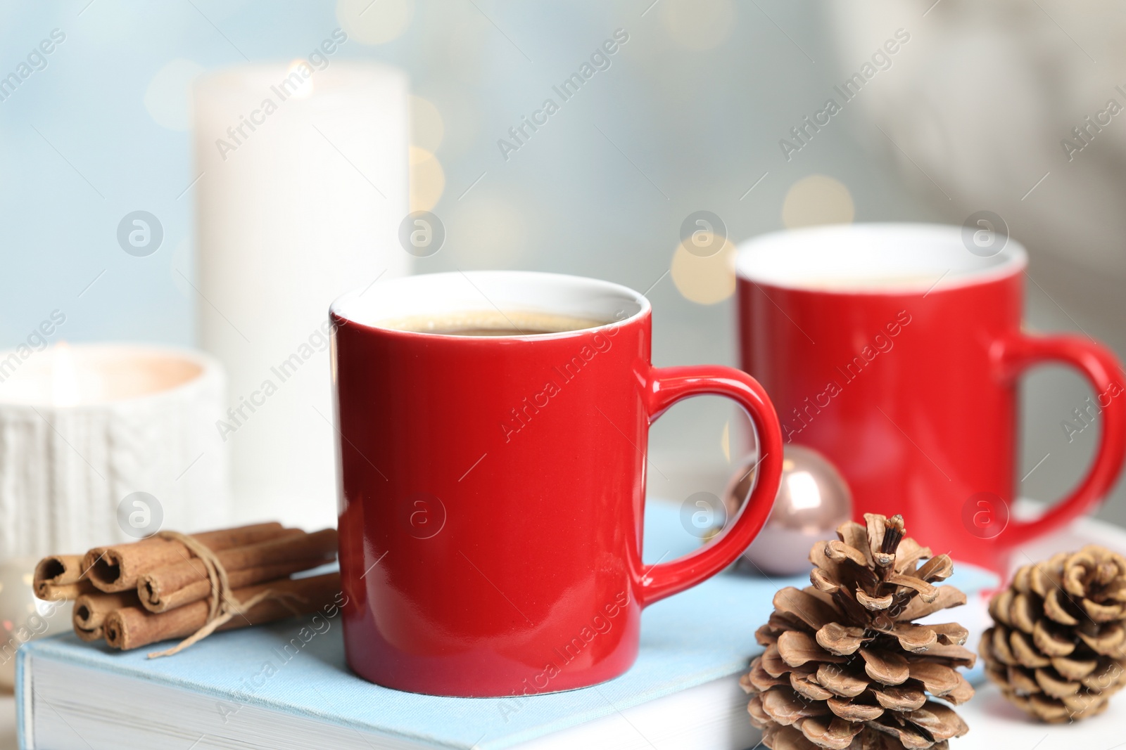 Photo of Cups of hot winter drink and Christmas decoration on table against blurred lights