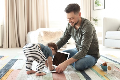 Dad and his son with laptop on carpet at home