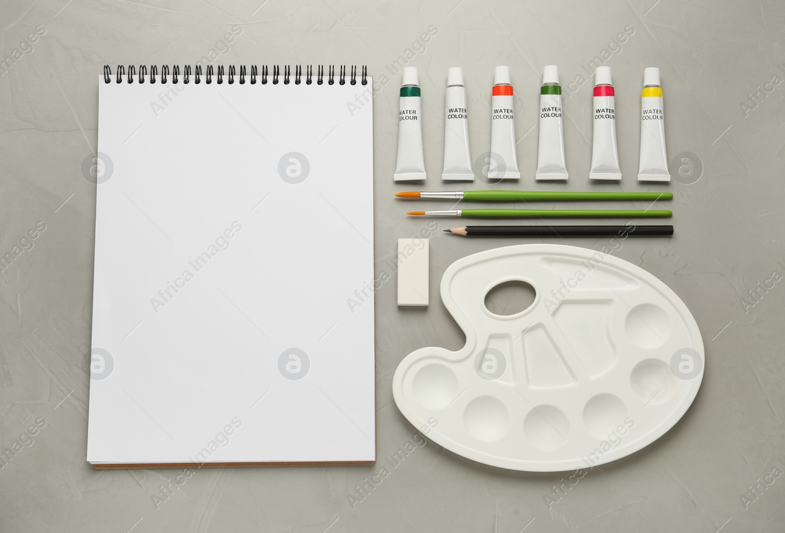 Photo of Flat lay composition with blank sketchbook on light grey stone table. Space for text