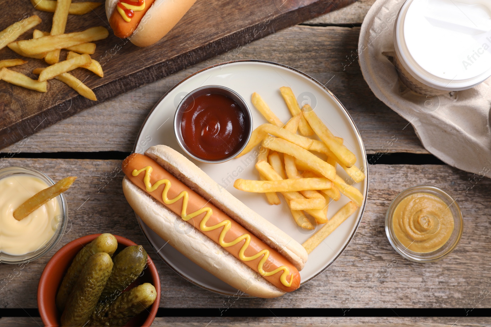 Photo of Flat lay composition with delicious hot dog and French fries on wooden table