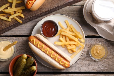 Flat lay composition with delicious hot dog and French fries on wooden table