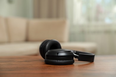 Photo of Modern wireless headphones on wooden table indoors