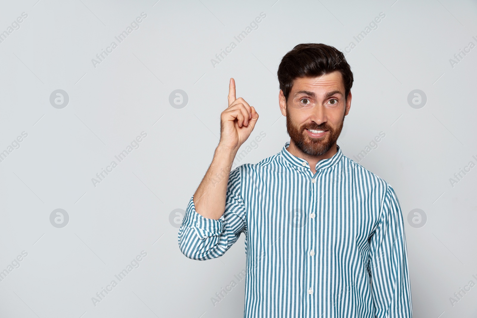 Photo of Bearded man pointing index finger up on grey background. Space for text