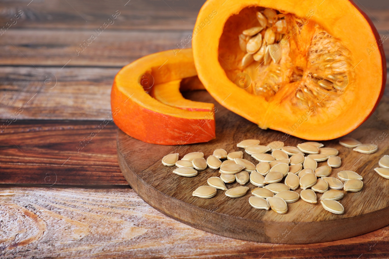 Photo of Fresh pumpkin and vegetable seeds on wooden table, closeup. Space for text