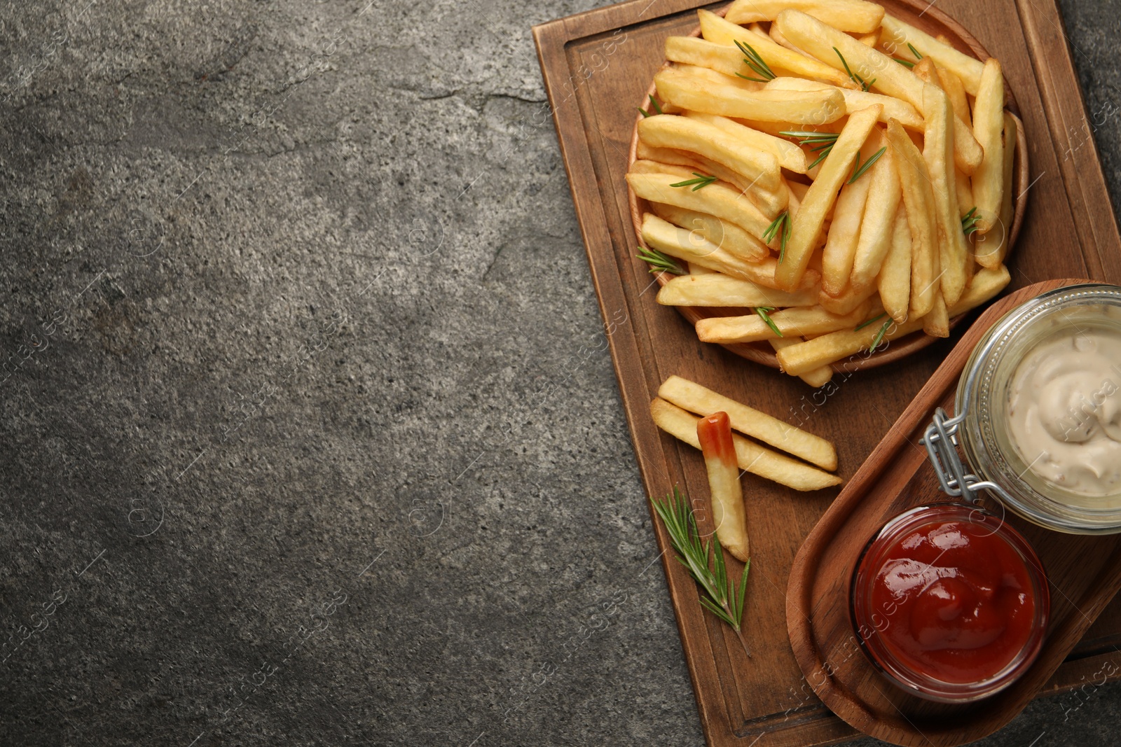 Photo of Delicious french fries served with sauces on grey textured table, top view. Space for text