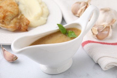 Photo of Delicious turkey gravy and garlic on white table, closeup