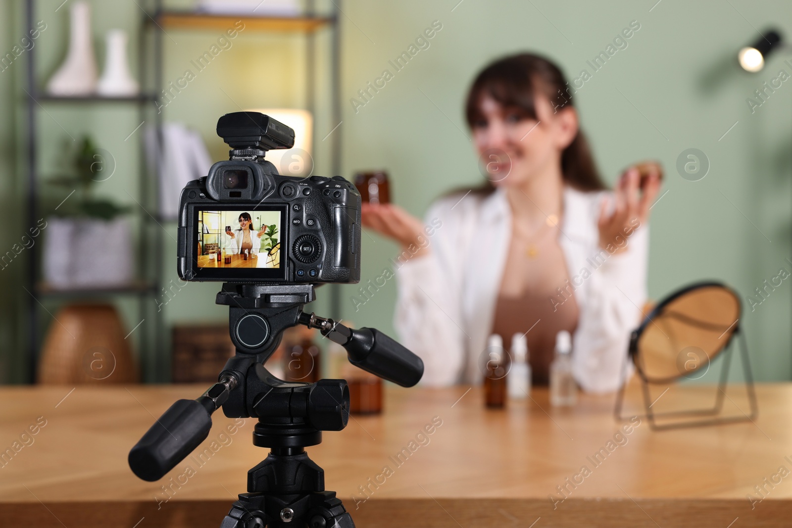 Photo of Beauty blogger recording video at home, focus on camera