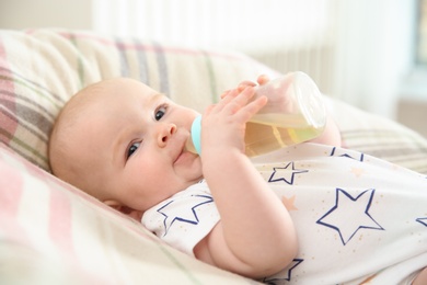 Photo of Pretty baby drinking from bottle on bed at home
