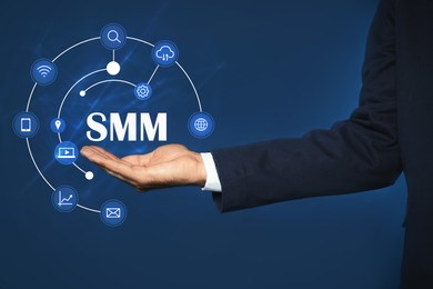 Social media marketing concept. Man holding virtual icon SMM on color background, closeup