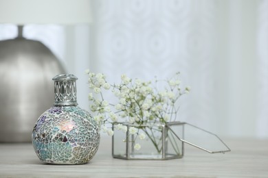 Photo of Beautiful catalytic purifying lamp and flowers on wooden table, space for text