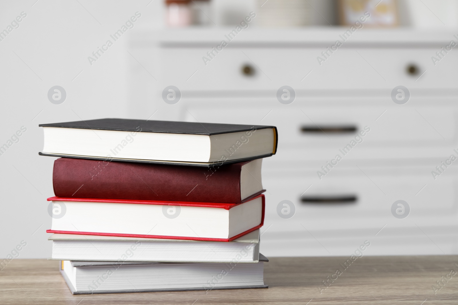 Photo of Stack of hardcover books on wooden table indoors, space for text