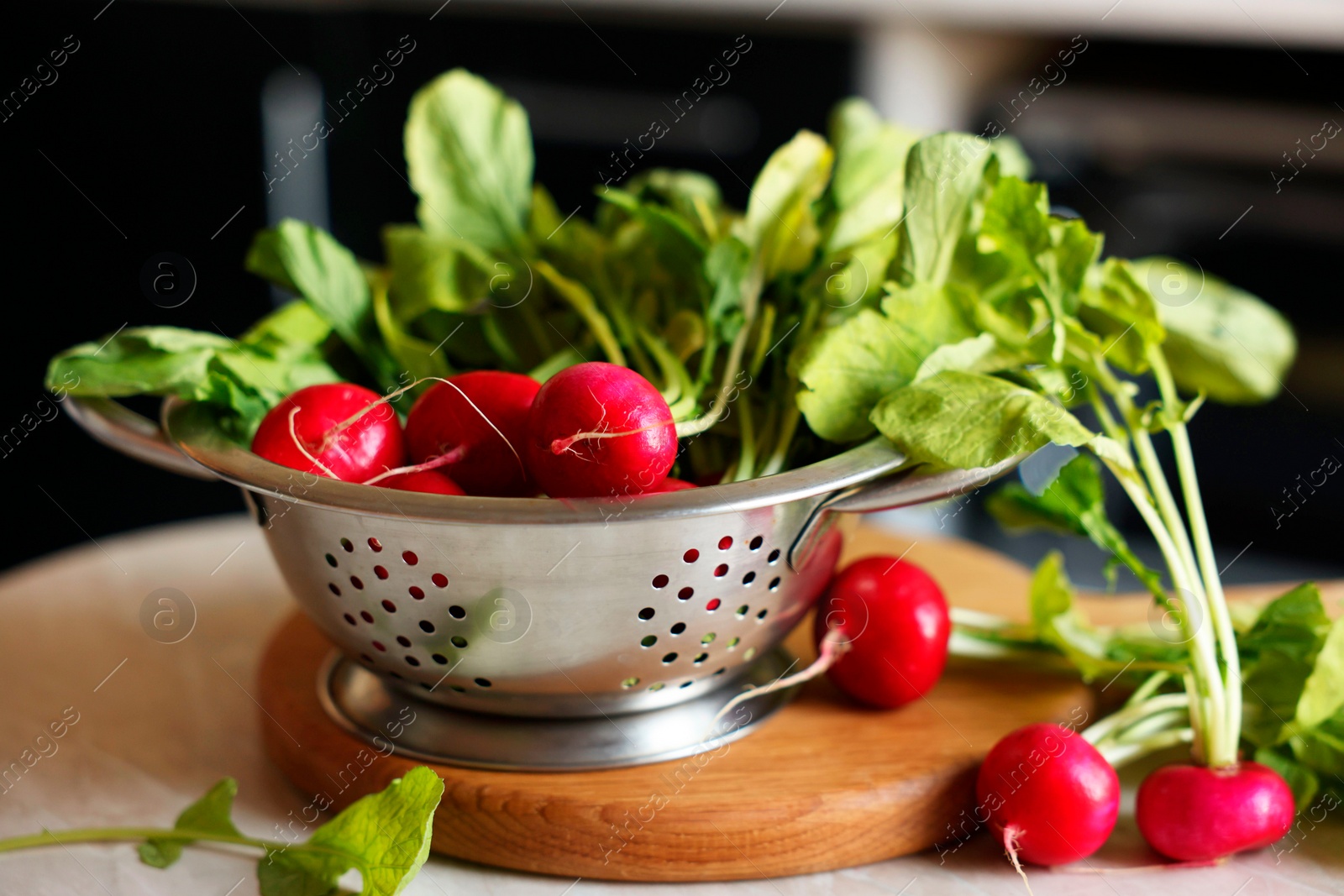 Photo of Metal colander with fresh radishes on white table, closeup