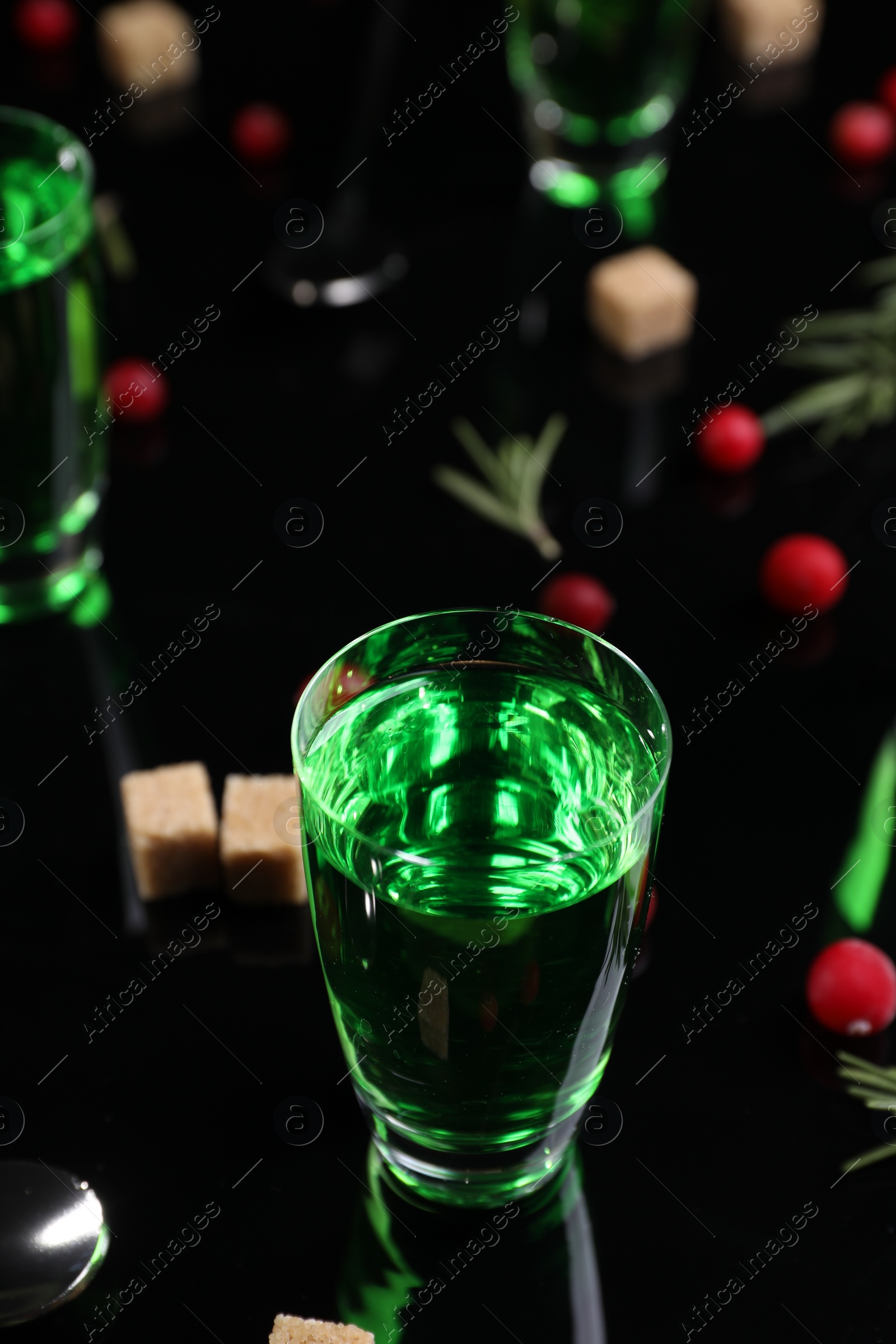 Photo of Absinthe in shot glass on mirror table, closeup. Alcoholic drink