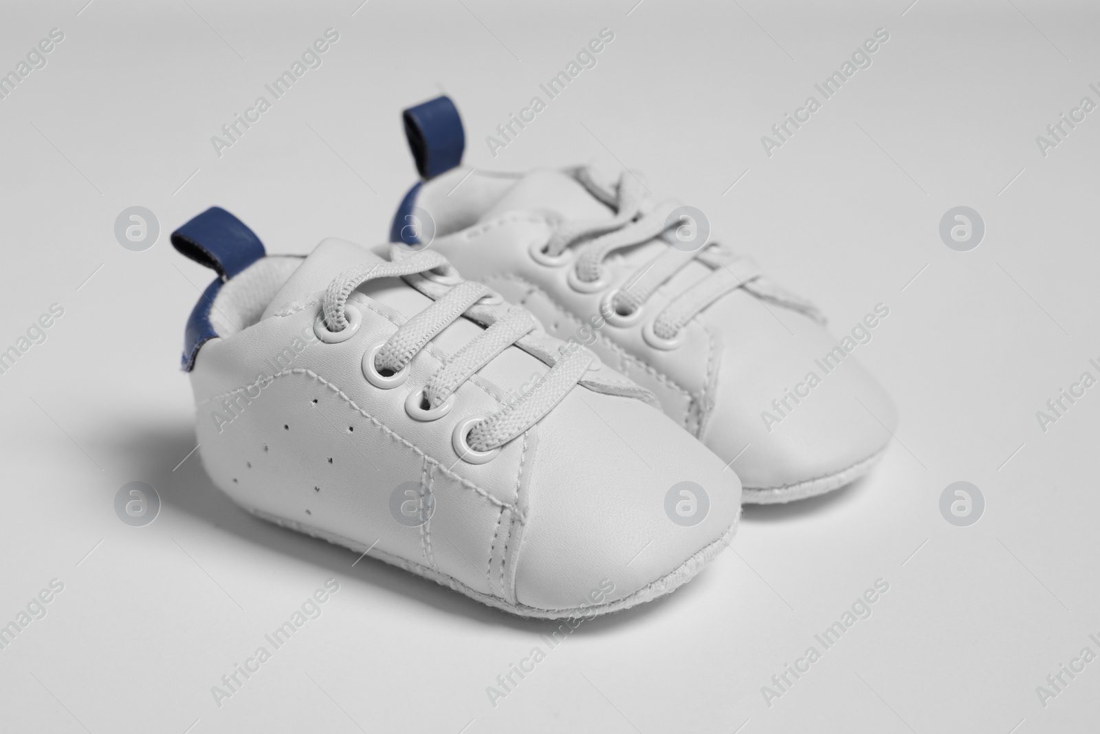 Photo of Pair of cute baby shoes on white background