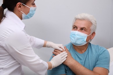 Doctor taking care of senior man with protective mask at nursing home