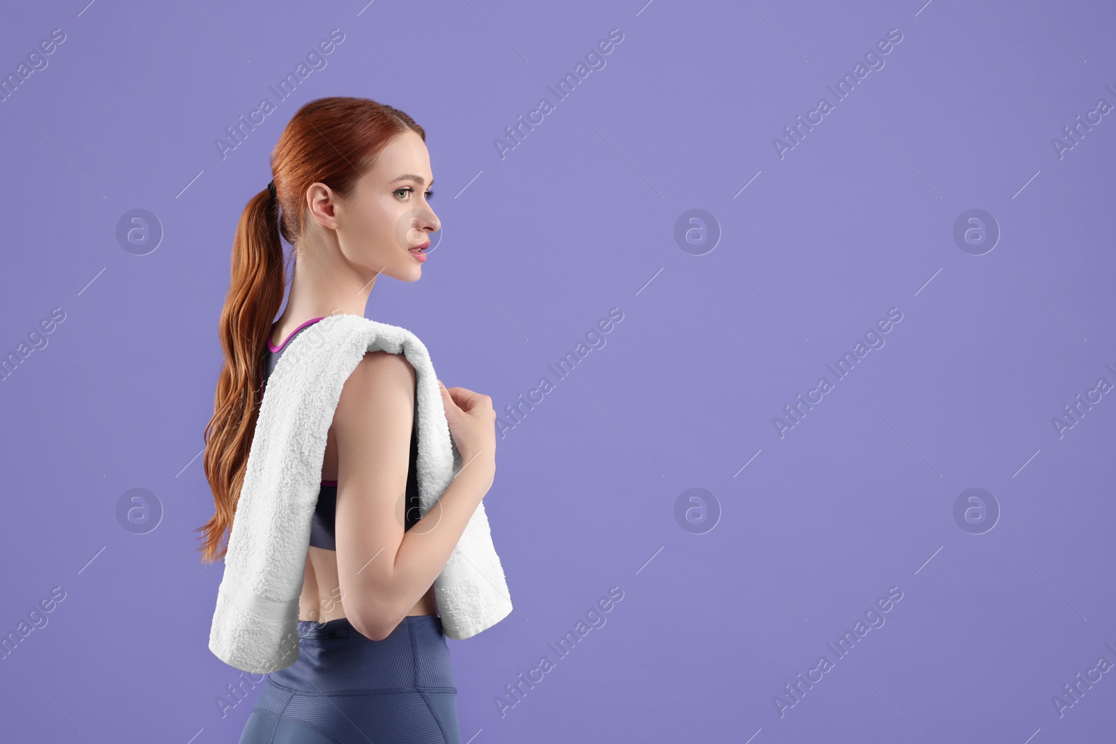 Photo of Woman in sportswear with towel on violet background, space for text