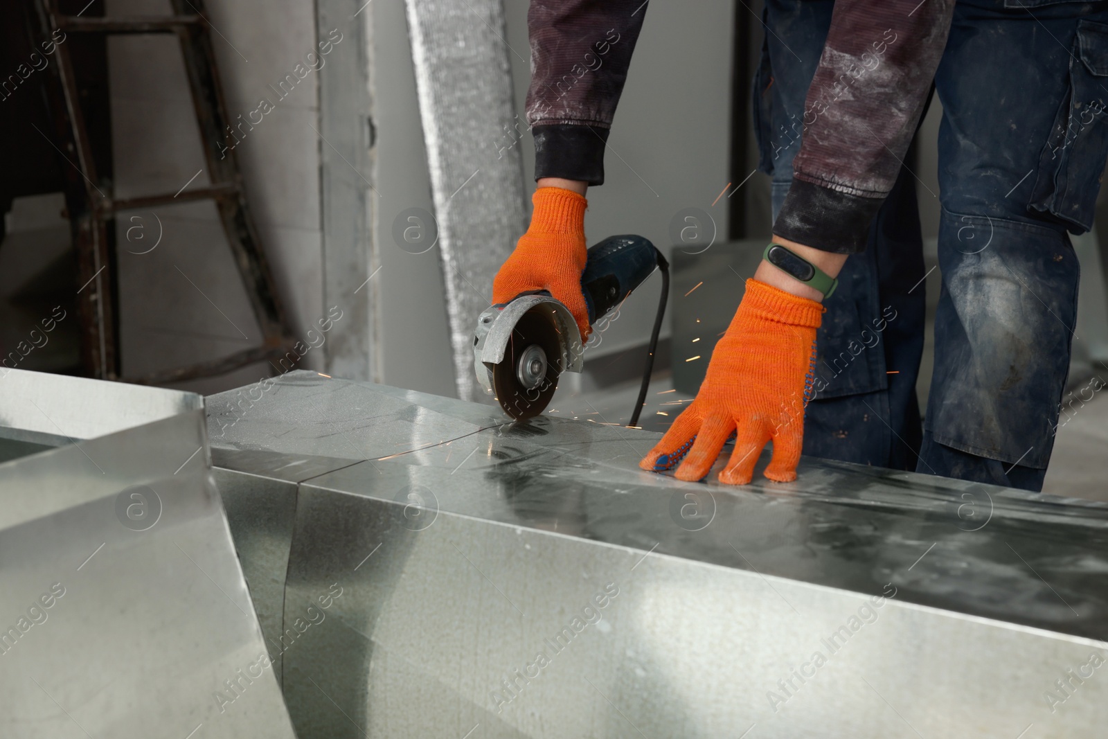 Photo of Worker cutting ventilation pipe indoors, closeup view