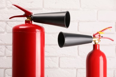 Photo of Fire extinguishers against white brick wall, closeup