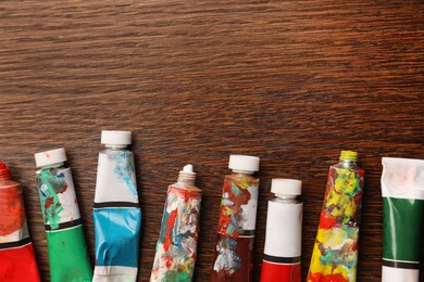 Photo of Tubes with oil paints on wooden table, flat lay. Space for text