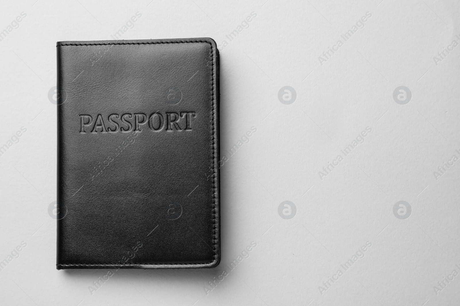 Photo of Passport in black leather case on light grey background, top view. Space for text