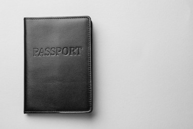 Passport in black leather case on light grey background, top view. Space for text