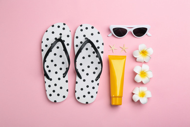 Photo of Flat lay composition with flip flops and beach accessories on pink background