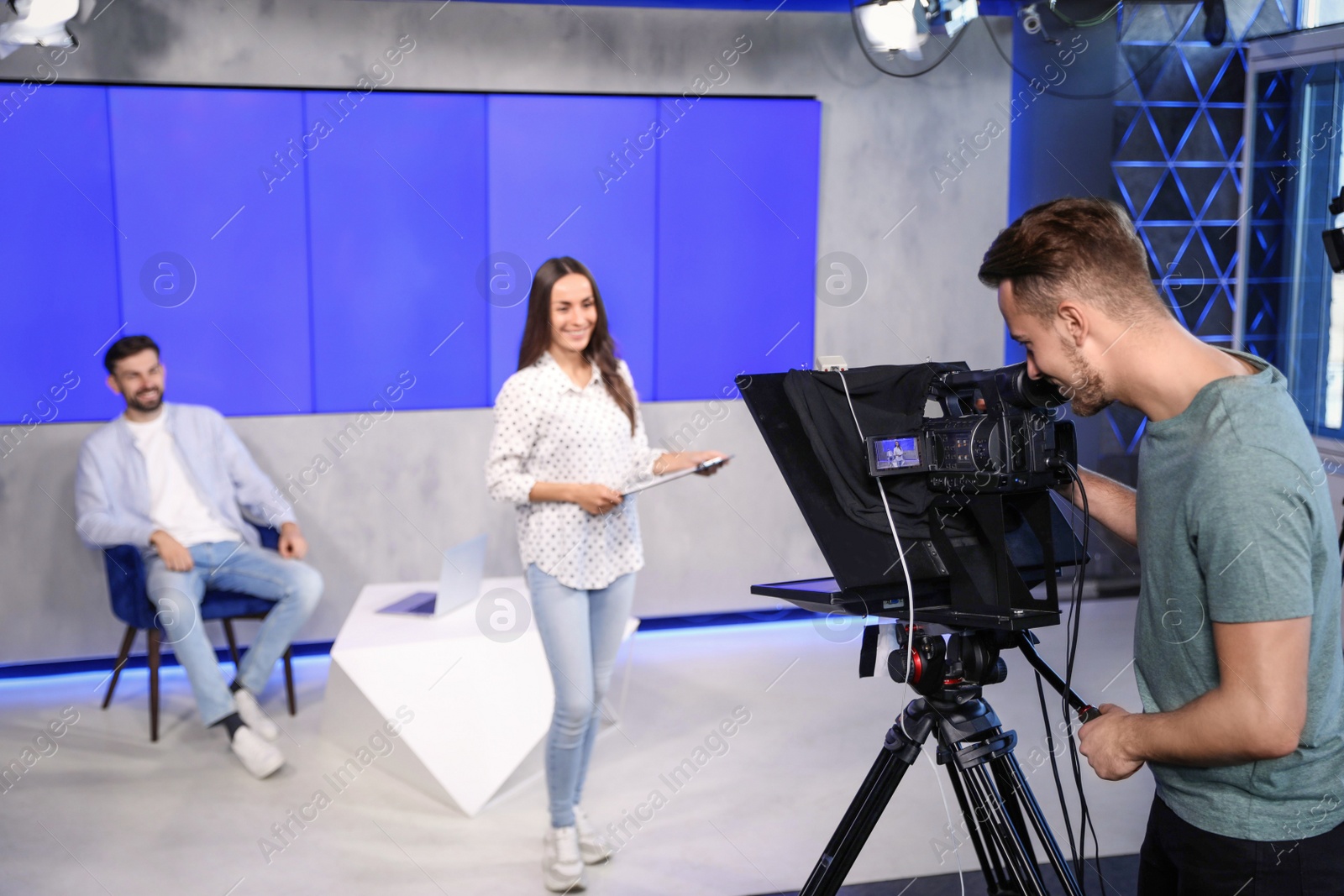 Photo of Presenters and video camera operator working in studio. News broadcasting